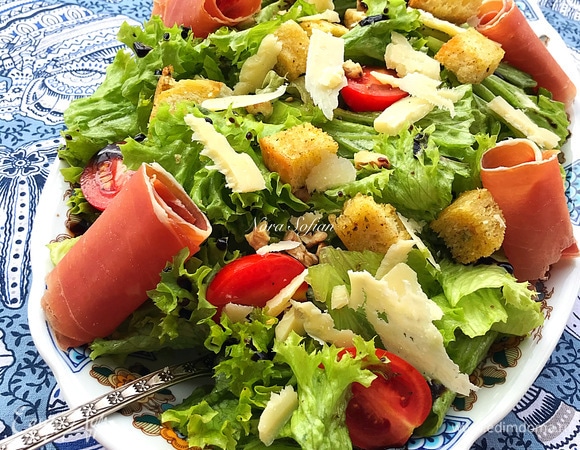 Затем переложить салат на блюдо, добавить орехи, тонко нарезанный сыр, сухарики, хамон и сбрызнуть бальзамическим соусом по вкусу.