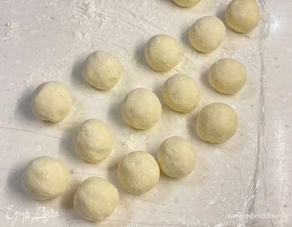 Поверхность стола застелить пищевой пленкой. Посыпать мукой. Из теста скатать одинаковые шарики размером чуть больше грецкого ореха.