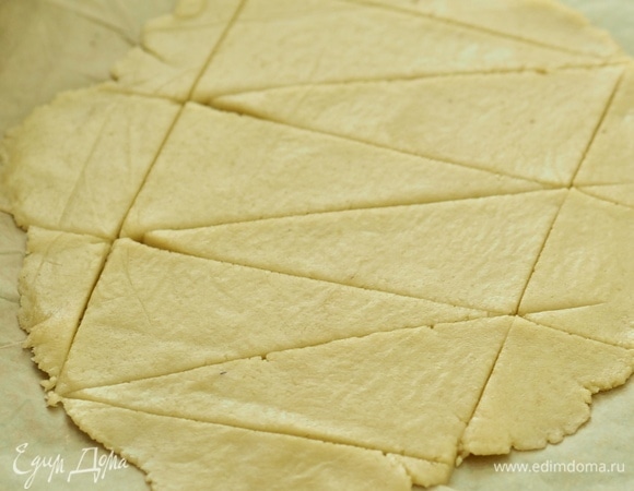 Охлажденное тесто раскатать в тонкий пласт между двумя слоями пергамента. Разрезать на небольшие треугольники. Выложить по половине чайной ложки начинки на каждый кусочек и свернуть рулетиком.