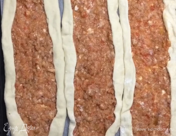 На тесто выкладываем часть начинки, равномерно распределяем, закрываем края и перекладываем на противень. Пиде непросто переложить на противень из-за тонкого теста и начинки, поэтому можете раскатывать сразу на бумаге для выпекания и на ней перекладывать на противень.