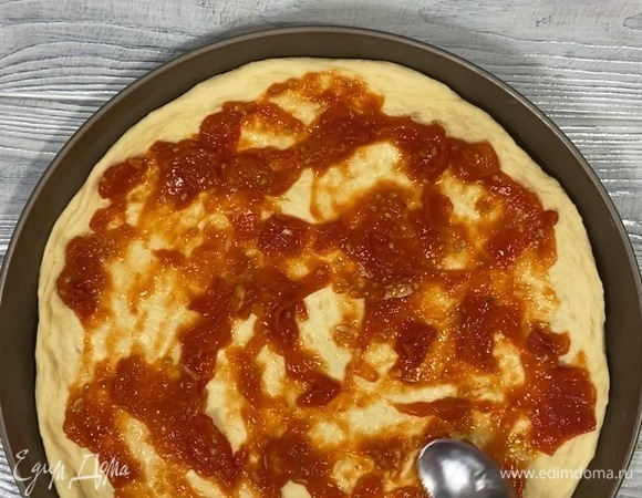 Помидор нарезать и потушить с томатной пастой и чесноком. Подошедшее тесто раскатать и выложить на противень, смазать соусом.