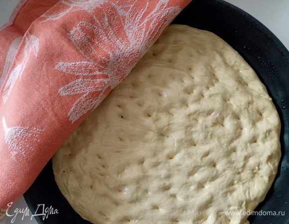 Форму смазать оливковым маслом. Выложить тесто и руками распределить по дну формы, делая пальцами небольшие вмятины. Накрыть полотенцем и дать постоять еще 30–40 минут.