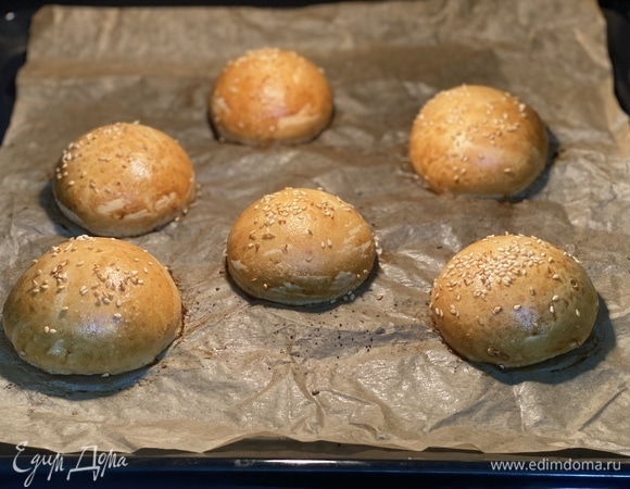 Духовку разогреть до 200°C. Подошедшие булочки смазать желтком, посыпать кунжутом и выпекать до румяной корочки примерно 15–20 минут. Остудить, разрезать пополам.