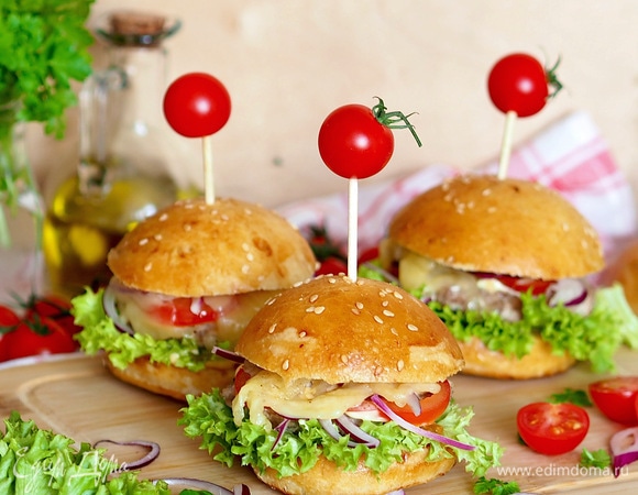 Формируем бургер: булочка, соус, салат, котлета, соус, лук, помидор, сыр, булочка. Здесь уже можно включить фантазию и собирать бургер в любой последовательности с любыми ингредиентами. Сыр я тонко режу, кладу на сухую сковороду и плавлю на ней, затем уже расплавленный сыр кладу на бургер.