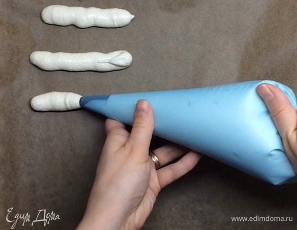 Выкладываем в кондитерский мешок с круглой насадкой. Если у вас нет мешка, то можете отрезать уголочек пакета и воспользоваться им. Застилаем противень пергаментной бумагой или силиконовым ковриком. И отсаживаем тонкие полоски по 8–10 см.