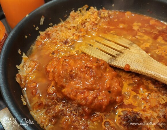 Когда почувствуется стойкий аромат, всыпать рис, тщательно перемешать. Добавить томаты в собственном соку, предварительно их измельчив, и айвар. Айвар — это паста из приготовленного на гриле болгарского перца. Продается в баночках, но можно сделать самостоятельно.