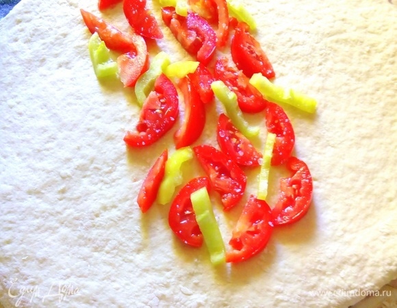 Делим тесто на две равные части. Раскатываем в круг толщиной около 2 см. Посередине выкладываем нарезанные полукольцами помидоры и сладкий перец. Накрываем одной половиной начинку, потом сверху — другой. Аккуратно соединяем края. Получается хлеб в виде батона. Делаем так же второй.