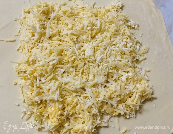Натираем сыр на крупной терке. Можно использовать несколько разных сортов. Если сыр не достаточно соленый, его можно посолить. Натертый сыр распределяем по центру и немного по краям.