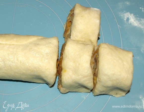 Сворачиваем в рулет. Смазываем край водой, соединяем. Нарезаем «улитками» шириной 3 см. Немного прижимаем.