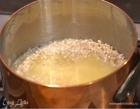 Перловку всыпать в сотейник, перемешать и слегка прогреть, чтобы крупа пропиталась маслом и ароматами, затем влить вино и дать алкоголю выпариться.