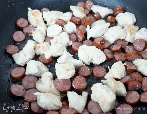 Филе индейки (можно заменить на курицу) нарезаем кубиком, колбаски — кружочками. Обжариваем с добавлением небольшого количества растительного масла.