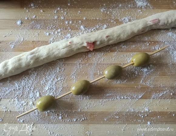 На шпажку надеть 4–5 оливок на небольшом расстоянии друг от друга. Из теста сделать небольшой жгут.