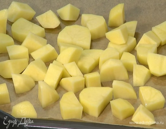 Картофель почистить и нарезать крупными брусочками, затем выложить на застеленный бумагой для выпечки противень и запекать в разогретой духовке 15–18 минут, практически до готовности.