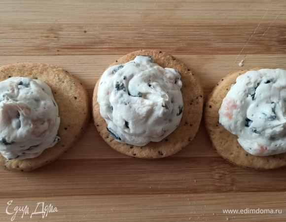 Оливки и 50 г рыбы мелко нарезать. Смешать с сыром. Переложить массу в кондитерский мешок и выдавить на печенье.