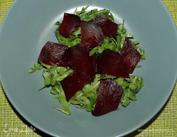 Свеклу заранее запечь в духовке. Руколу промыть и дать стечь воде. Руколу выкладываем в тарелку. Свеклу нарезать тонкими слайсами. Выкладываем на руколу.