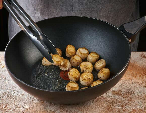 Обжарьте гребешки на раскаленной сковороде с добавлением оливкового масла по одной минуты с каждой стороны.