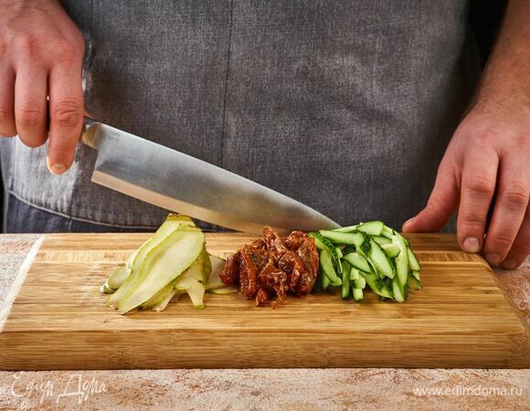 Вяленые помидоры обмакните бумажным полотенцем, чтобы убрать лишнее масло. Нарежьте кусочками. Огурец вымойте, нарежьте соломкой. Груши очистите от кожицы и тоже нарежьте соломкой.