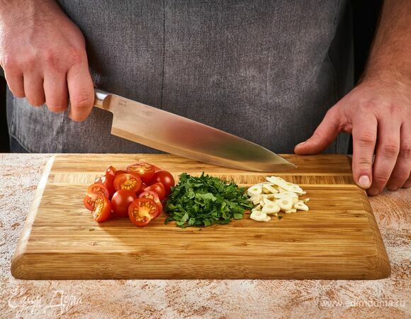 Зубчики чеснока измельчите. Зелень порубите. Помиодоры черри разрежьте пополам.