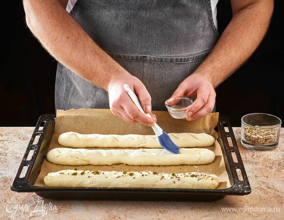 Смажьте заготовки водой и посыпьте смесью семян. Оставьте еще на 10 минут. Выпекайте багеты в течение 7 минут при 220°С, затем еще 25 минут при 180°С.