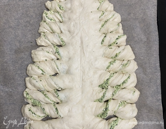 Ножом (специальным прибором для пиццы будет удобнее) сделать с обоих краев одинаковые надрезы, не доходя до середины, и завернуть края. Смазать желтком.