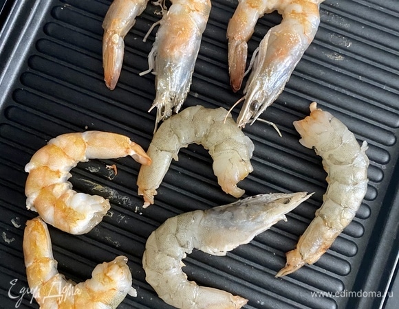 Листья салата вымыть и просушить. Крупно нарвать руками. Креветки очистить, убрать кишечную вену. На сковороде-гриль разогреть оливковое масло, добавить крупно нарезанный зубчик чеснока и быстро обжарить. Черри вымыть, разрезать пополам. Пармезан нарезать на тонкие слайсы. Орешки слегка поджарить на сухой сковороде. Для заправки смешать все ингредиенты до состояния эмульсии. 