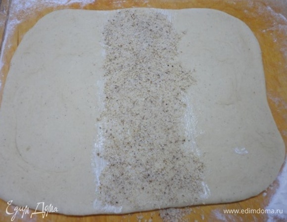 Для начинки в блендере измельчить орехи с сахаром. Подошедшее тесто разделить на две части. Каждую раскатать в прямоугольник и смазать сливочным маслом. Среднюю третью часть теста посыпать орехами.