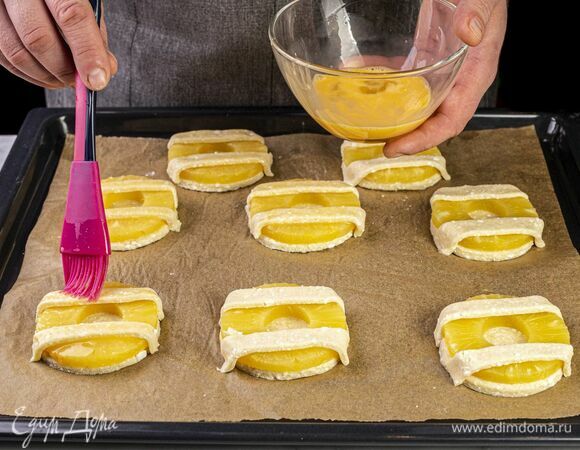 Куриное яйцо взбейте вилкой, смажьте им полоски теста.
