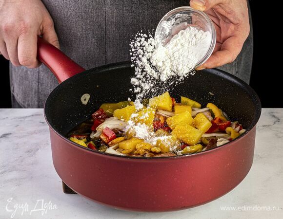 Добавьте крахмал. Перемешайте, посолите, поперчите. Томите содержимое сковороды под крышкой до готовности свинины.