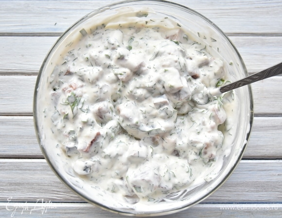 В сметанную заливку добавить молотый мускатный орех, кусочки сельди, нарезанный лук и зелень. Перемешать.