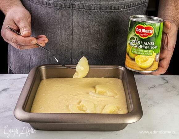 В форму для кекса, выстеленную пекарской бумагой, выложите тесто. Откройте банку с половинками груш в легком сиропе Del Monte (415 г), слейте сироп и выложите груши на тесто, притопите.