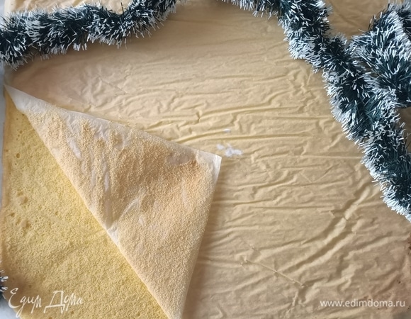Готовый бисквит достать, перевернуть его нижней стороной вверх и выложить на пергаментную бумагу. Дать остыть. Затем аккуратно снять верхний слой пергамента.