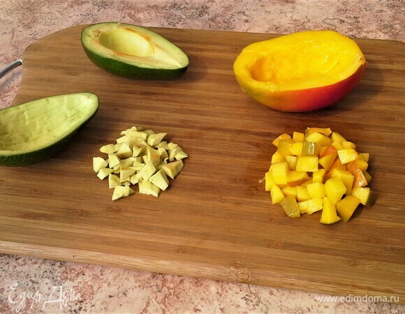 Авокадо разрежьте пополам, удалите косточки. Аккуратно извлеките мякоть из каждой половинки, и нарежьте мелкими кубиками, сбрызните соком лайма, кожуру не выбрасывайте. Кубиком нарежьте мякоть манго.