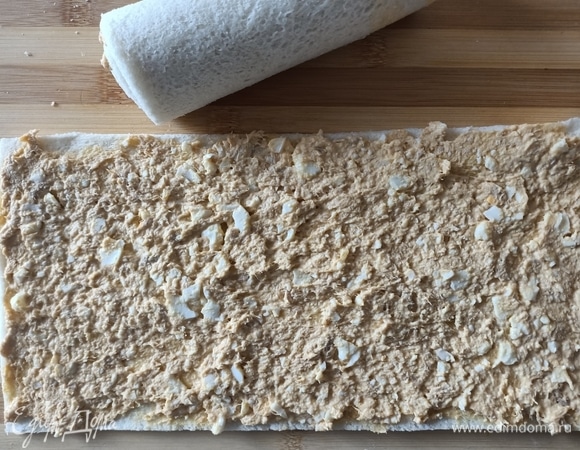 Далее необходимо сделать начинку: с тунца слить жидкость, добавить одно вареное яйцо, все измельчить с помощью вилки, добавить майонез и перемешать. Выложить начинку на два прямоугольных тоста и распределить ее. Аккуратно свернуть хлеб в рулеты.