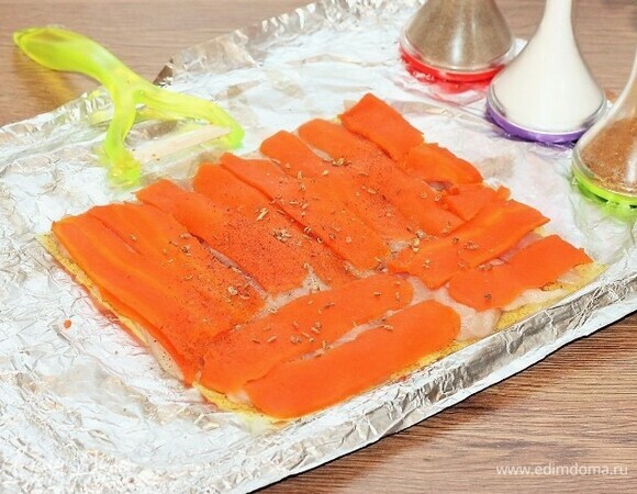 Вареную морковь с помощью овощечистки нарезаем длинными пластинами и выкладываем на курицу, посыпаем приправой для овощей, перцем и солью.