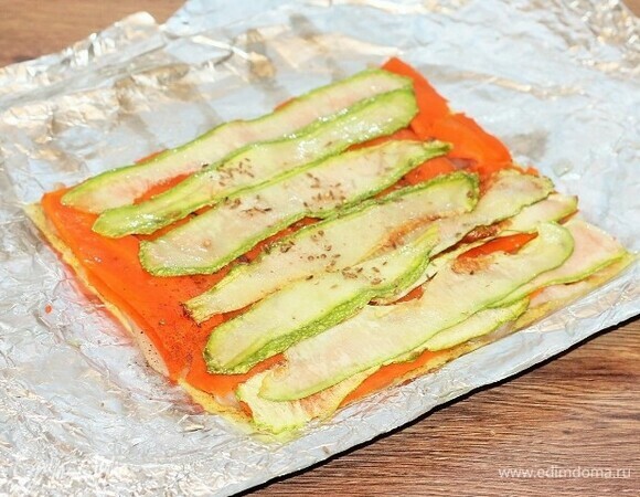Кладем пластины кабачка на морковь, посыпаем приправой для овощей, перцем и солью.
