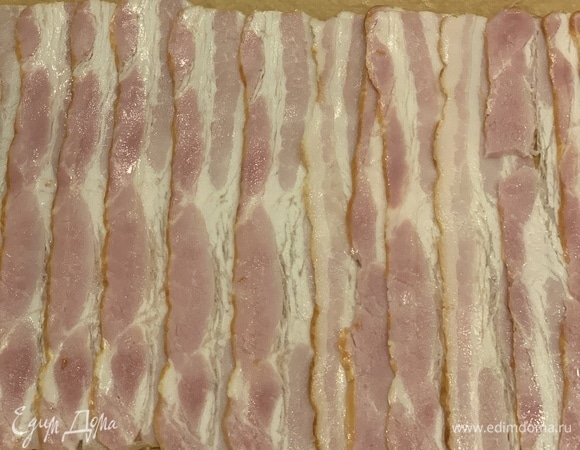 Выкладываем на середину пергаментного листа бекон внахлест.