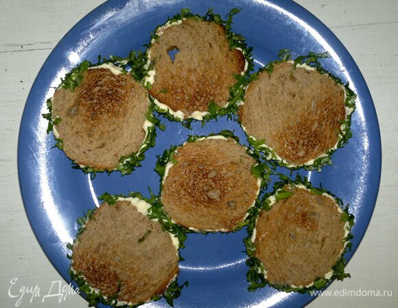 Боковую часть кусочков хлеба смазать майонезом. Обвалять в нарезанной зелени.