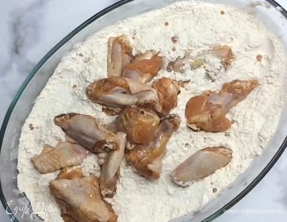 Выкладываем куриные крылья, перемешиваем и перекладываем в дуршлаг.
