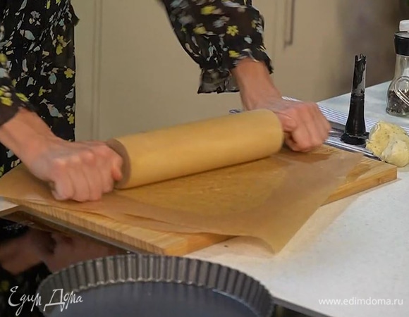 Вымесить тесто руками, поместить между двумя листами бумаги для выпечки и раскатать скалкой в тонкий пласт.