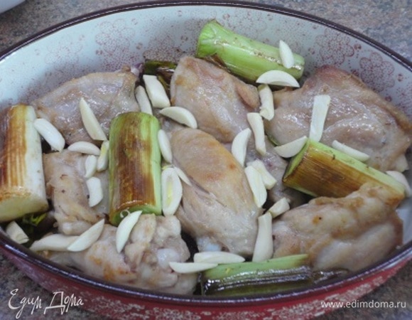 Выложить порей к курице, равномерно распределить крупно нарубленный чеснок.