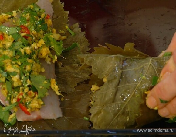 Филе рыбы нарезать порционными кусками, уложить каждый на несколько виноградных листьев, сверху выложить пряную смесь, свернуть в рулетик и скрепить зубочистками.