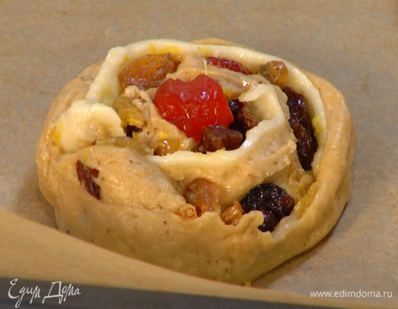 На тесто выложить пласт марципана, посыпать цедрой, разложить по всей поверхности изюм с вишней и свернуть тесто в рулет, нарезать его на ломтики толщиной 2 см и выложить на противень, выстеленный бумагой для выпечки.