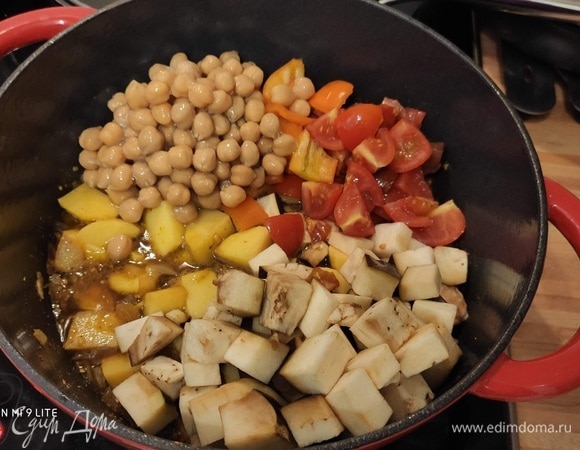 Очищенный картофель нарезать на порционные кусочки, выложить в кастрюлю, затем добавить нарезанные помидоры и баклажаны, а также сваренный заранее или консервированный нут. Все хорошо перемешать и тушить под крышкой в разогретой в течение 30–45 минут. При необходимости добавить еще немного овощного бульона. У нас кастрюля после готовности блюда стояла еще некоторое время, и рагу получилось кремовым и нежным.