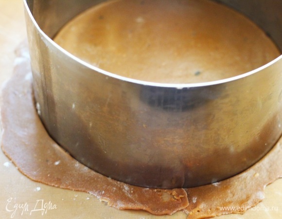 Раскатать тесто толщиной 2–4 мм на пекарской бумаге и вырезать круг при помощи кольца диаметром 16 см. Мы выпекаем по два коржа на одном противне.