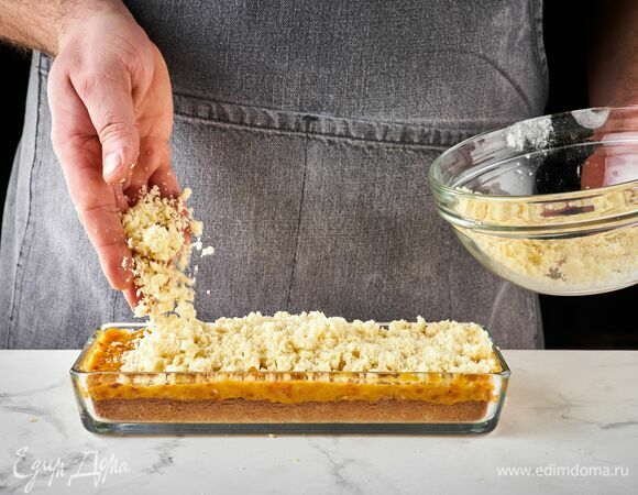 Поверх начинки выложите штрейзель. Выпекайте десерт 20 минут при 180°С до румяного цвета.