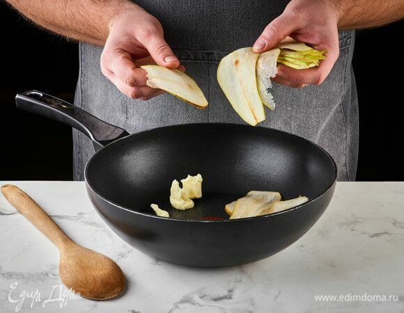 Очистите грушу от сердцевины и нарежьте тонкими слайсами. На сковороде разогрейте сливочное масло, выложите кусочки груши.