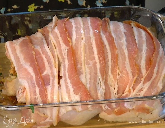 Тушку цыпленка посолить и поперчить снаружи и внутри, плотно наполнить начинкой и скрепить зубочисткой. На тушку выложить оставшийся бекон, сверху накрыть фольгой.