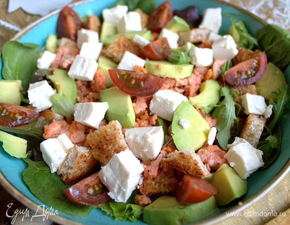 Рассыпать по салату фету, дольки томата и авокадо, оставшиеся сухарики также.
