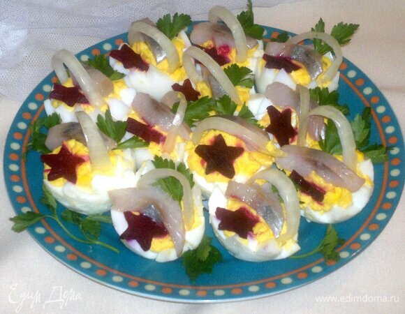 В начиненные половинки яиц выложить кусочки сельди и «звездочки» свеклы. Вставить лук. Украсить листиками петрушки. Подать закуску к столу. Приятного аппетита! С наступающим Новым годом!