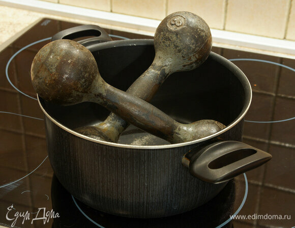 На сковороду выложить тушку цыпленка спинкой вверх, сверху придавить гнетом (можно использовать любые подручные предметы, например, тяжелую ступку, кастрюльку с водой или гантели).